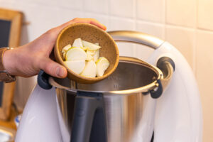 Zwiebel und Knoblauch in den Mixtopf geben
