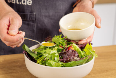 Dressing auf den Salat geben
