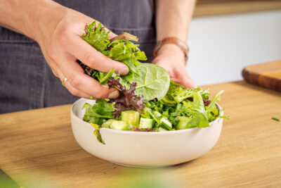 Salat mit dem Gemüse in eine Schüssel geben