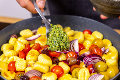 Pesto und Gemüse zu den Gnocchi geben