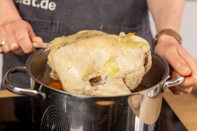 Suppenhuhn aus dem Topf nehmen
