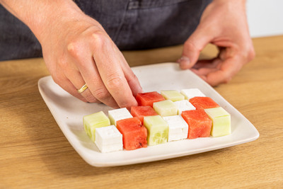 Melone, Feta und Gurke immer abwechselnd auf den Teller geben