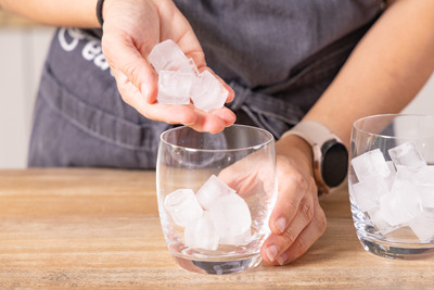 Eiswürfel in Gläser geben