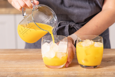 Orangensaft in Gläser gießen