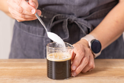 Zucker in Espresso geben