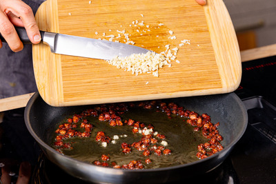 Knoblauch in die Pfanne geben