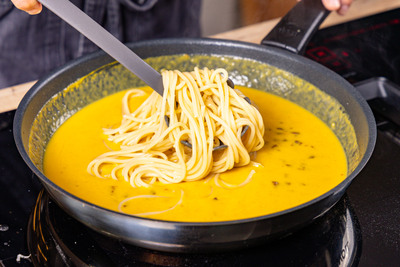 Spaghetti mit Kürbis Carbonara vermengen