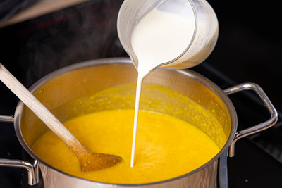 Sahne zur Kürbissuppe gießen