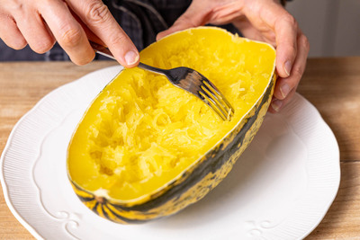 mit einer Gabel die Fäden des Spaghettikürbis ziehen