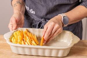 Kürbis und Kartoffeln in Auflaufform schichten