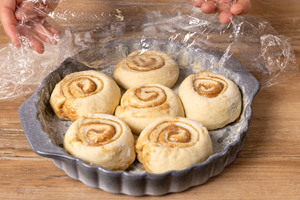 Teigschnecken mit Frischhaltefolie vor dem Backen abdecken